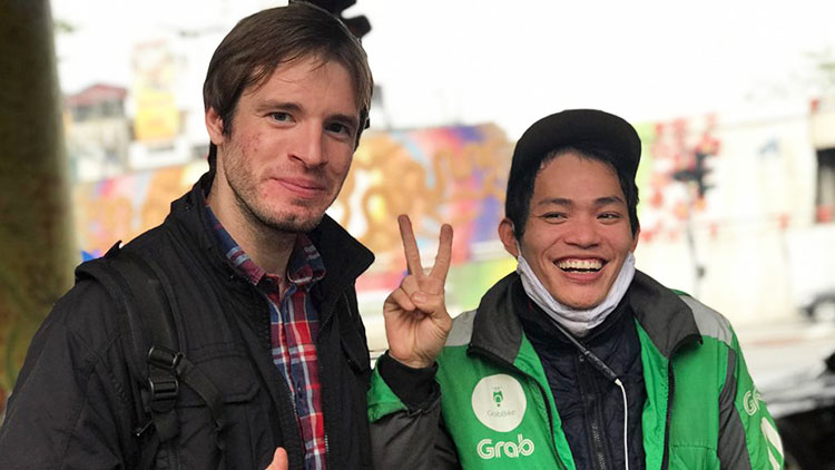 A tourist taking photos with a Grab driver