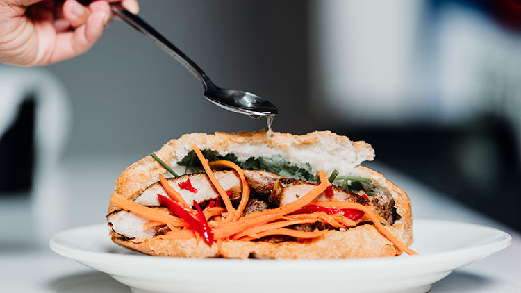 a person is adding fish sauce to Banh Mi