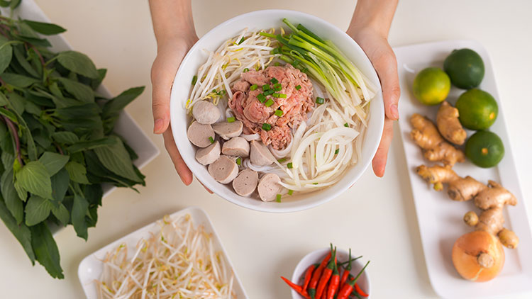 a person is holding a bowl of Pho
